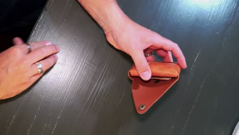 a man placing euro banknotes into a handcrafted leather wallet that he made himself