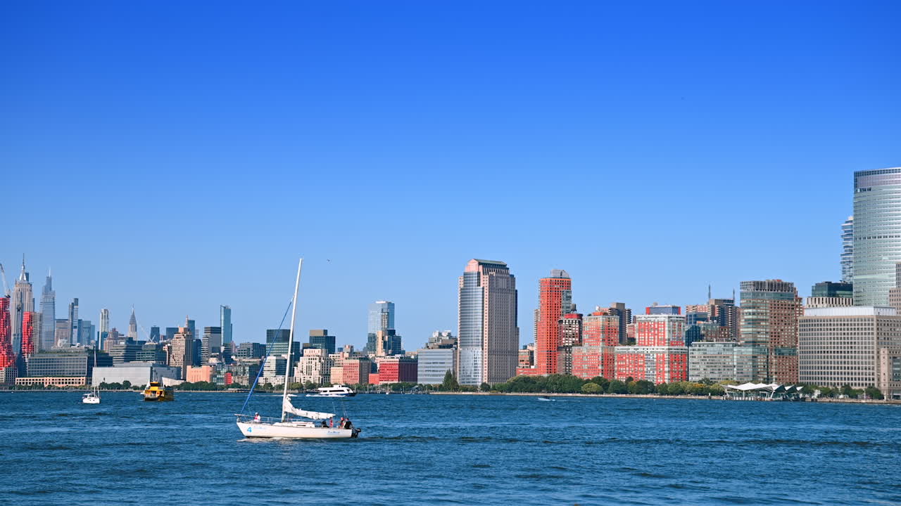 New Jersey, USA, 19 August 2025: Motorboats and sailboats travel by the East River on a clear sunny day. New York skyline at backdrop