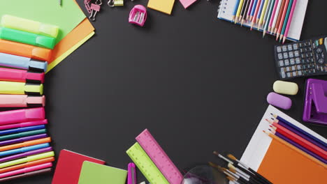 video of school supplies and notebooks, paper clips, pens over black background