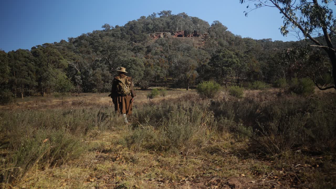 un hombre tradicional australiano caminando por las montañas en el desierto australiano