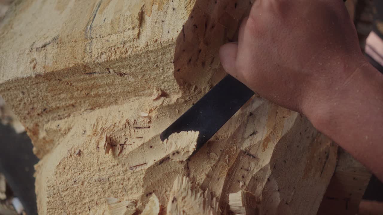 Skillful hands of a Balinese wood carver using a curved chisel and mallet on woodworking to make Barong Bangkung, a traditional dance wooden mask
