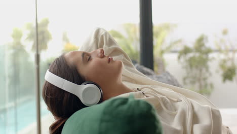 relaxing on couch, woman wearing headphones and enjoying music at home