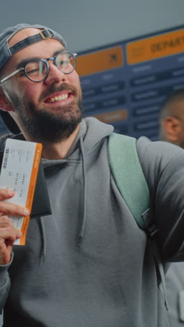 man taking a selfie at the airport with his boarding pass.