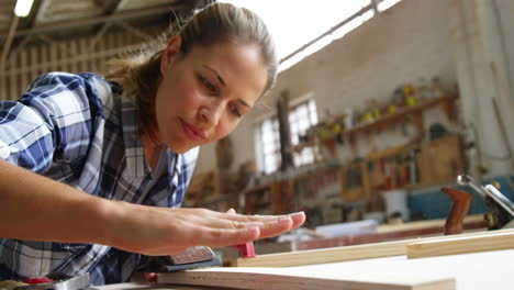 beautiful carpenter blowing on wooden plank