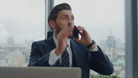 annoyed business man calling phone sitting at work desk closeup. nervous manager