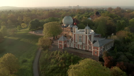 Kreisende-Luftaufnahme-Des-Greenwich-Observatoriums-Mit-Hintergrundbeleuchtung-Bei-Sonnenaufgang