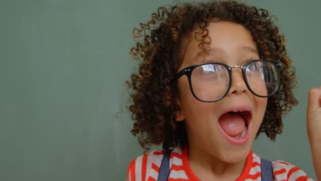 Front-view-of-mixed-race-schoolgirl-with-spectacle-shouting-in-classroom-at-school-4k