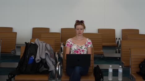 joven mujer caucásica trabajando en una computadora en el aeropuerto