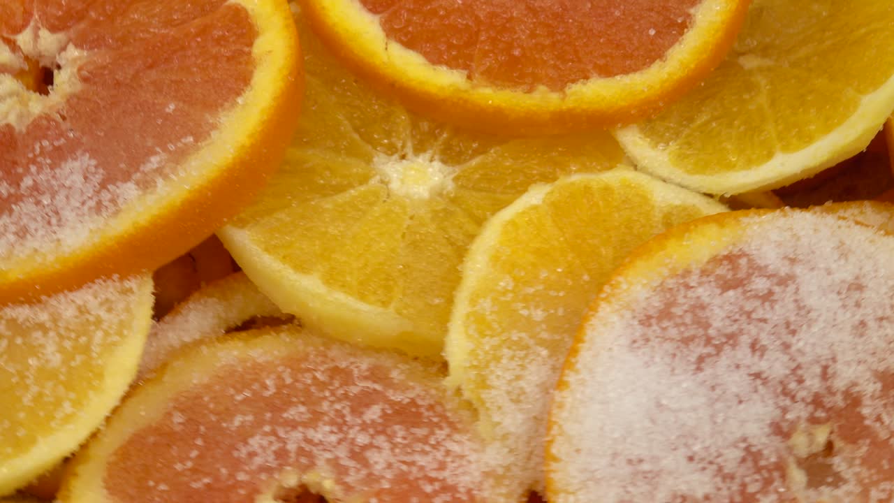 las rebanadas de naranja salpicadas de azúcar se encuentran en capas en un recipiente de cobre para hacer mermelada.