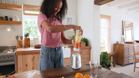 woman blending smoothie in kitchen, smiling and enjoying cooking, at home