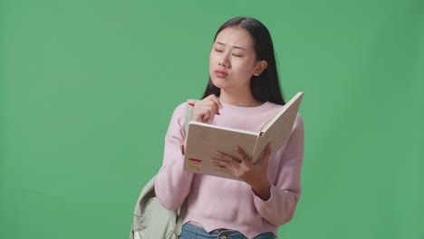 asian woman student note on book and thinking in green screen studio