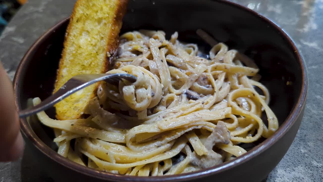 Closeup of a twirling delicious fresh tagliatelle with creamy truffle sauce pasta dish onto fork at Italian restaurant