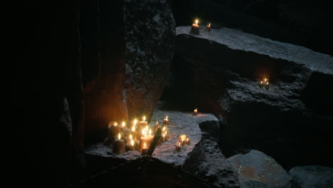 candles illuminate rocks in a dark cave during a serene moment of tranquility