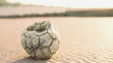forgotten soccer ball rests on sandy shore at sunset with warm glow