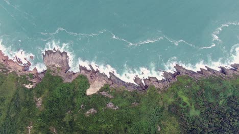 Aerial-view-of-a-jagged-rock-island,-surrounded-with-lush-green-nature-and-Hong-Kong-bay-water