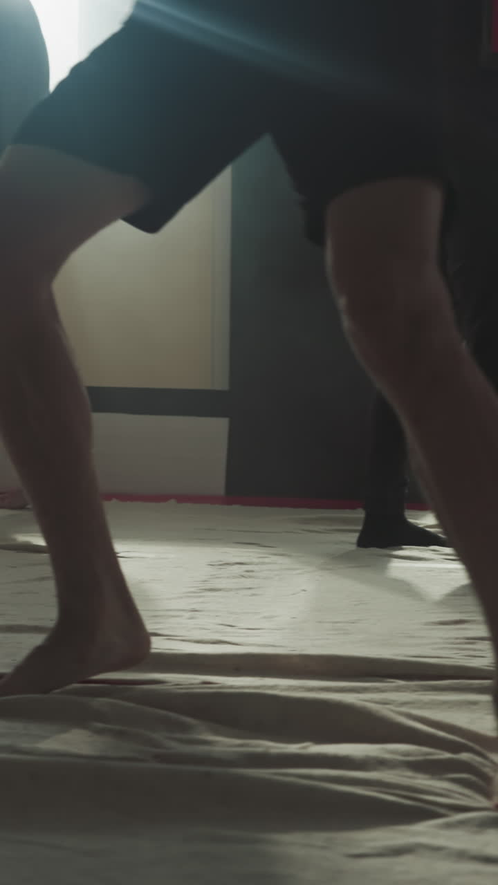 los luchadores entrenan pateando bolsas de boxeo en clubes deportivos de cerca. los kickboxers hábiles hacen ejercicios en grupo con objetos pesados en el gimnasio de lucha en cámara lenta