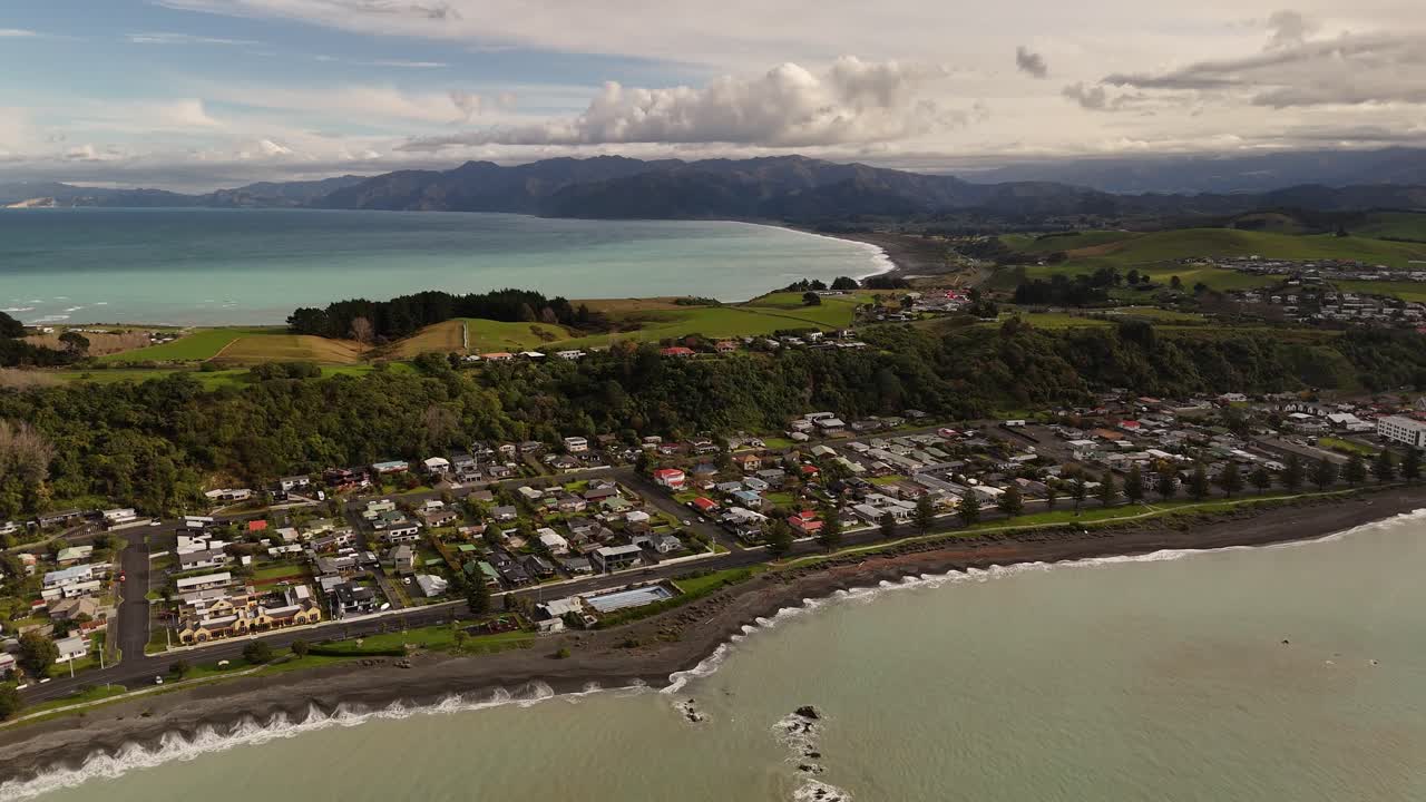 Kaikoura coastal town, bay, dark beach, peninsula, New Zealand. Aerial backward