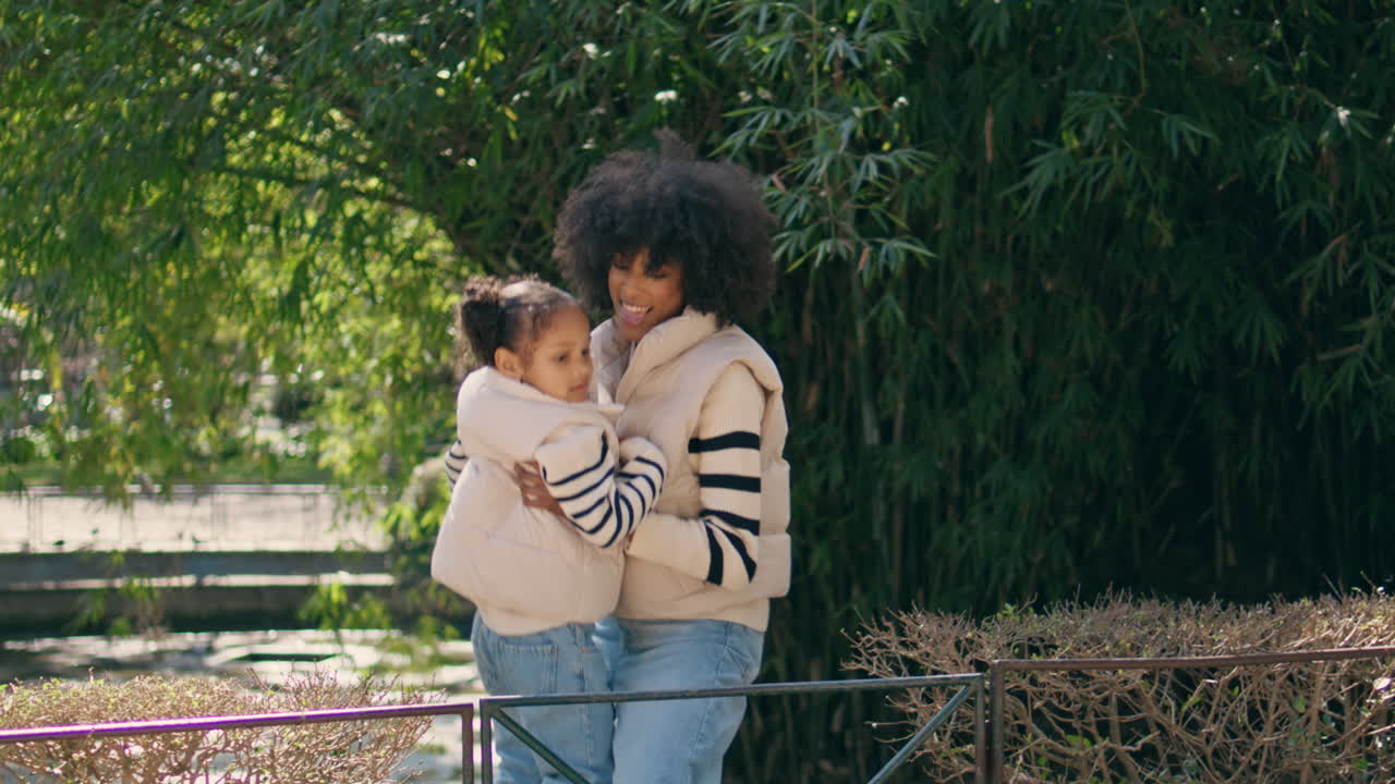 mujer llevando a su hija caminando trasplantando por encima de la valla. mamá se divierte con el niño