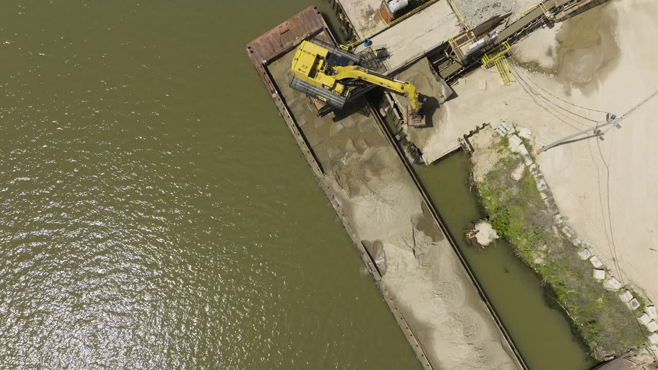vista aérea de la excavadora descargando grava de la barcaza en el pozo a cielo abierto