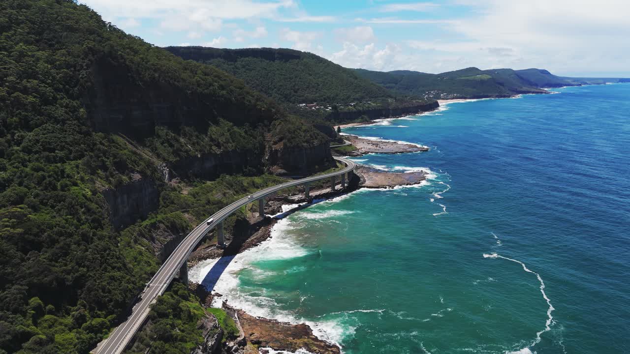 Aerial: Sea Cliff Bridge during the day on Lawrence Hargrave drive to Wollongong in the region of New South Wales, Australia, establishing drone shot