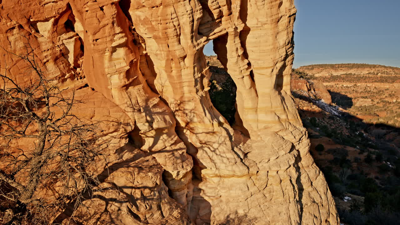 Breathtaking drone footage of a sandstone arch silhouetted against a fiery sunrise in Utah.