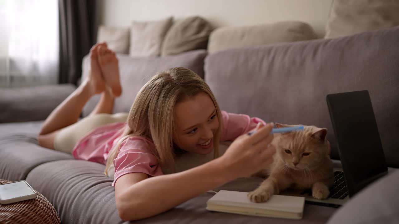 소파에서 고양이와 함께 공부하는 십대 소녀
