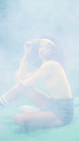 vertical video: young woman in casual outfit sitting in misty studio, embracing retro vibes