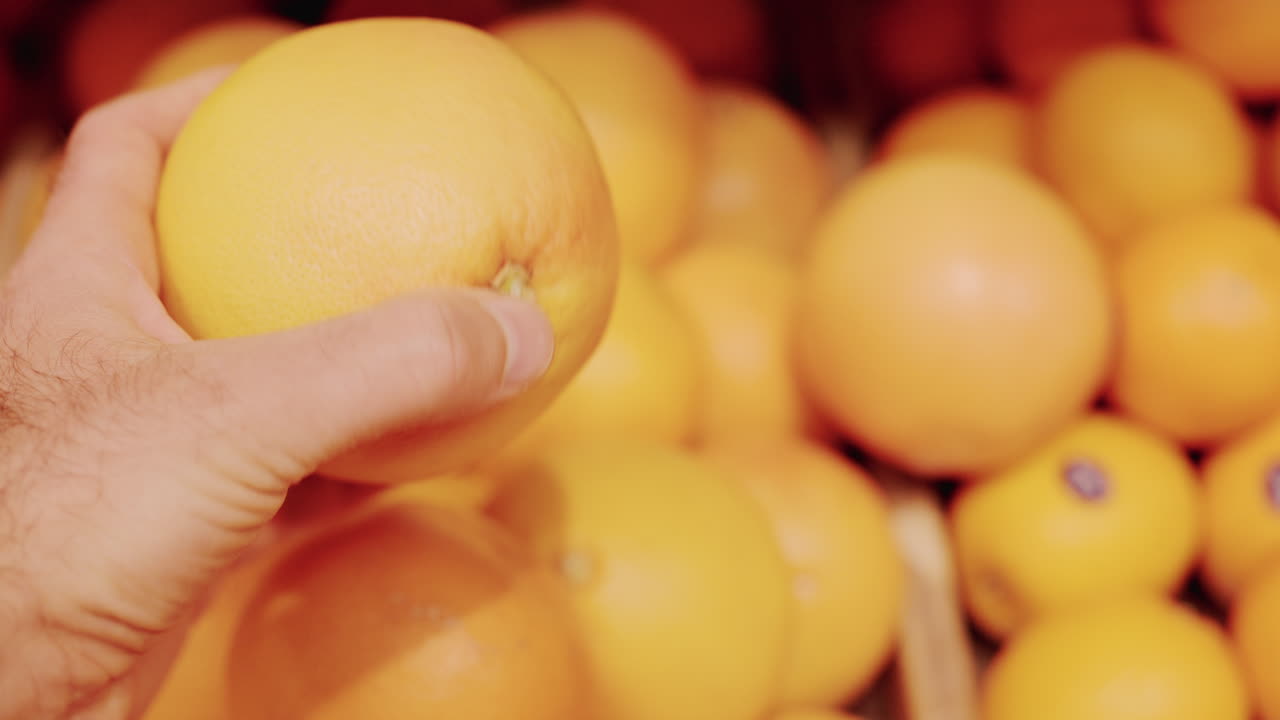 Close up of a hand holding a bright orange fruit in a market