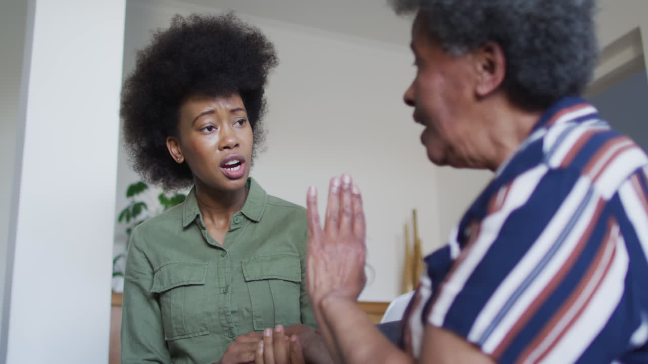 hija adulta afroamericana y madre mayor decepcionada en discusión en casa, cámara lenta