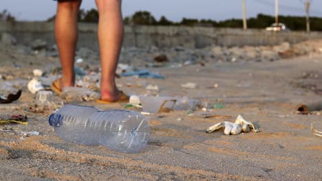 a plastic bottle is thrown away by a white tourist on a sandy beach