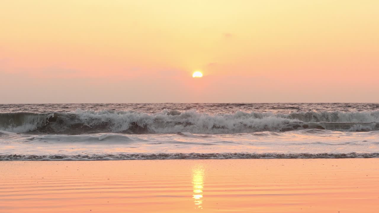 beautiful view of the ocean with waves rolling and sun going down on the horizon