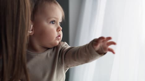 video de un bebé caucásico guapo mirando por la ventana en su casa.