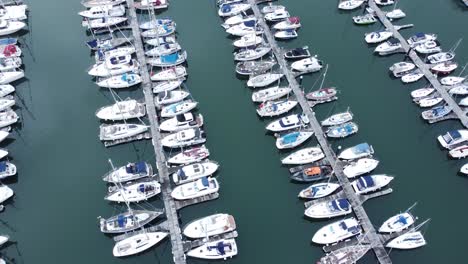 Top-down-aerial-view-above-luxury-yachts-parked-on-turquoise-ocean-water-marina-rotating-left