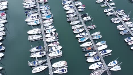 vista aérea de arriba hacia abajo sobre yates de lujo estacionados en un puerto deportivo de aguas turquesas girando a la izquierda