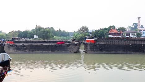 el barco de carga se mueve a lo largo de la orilla del río ayutthaya