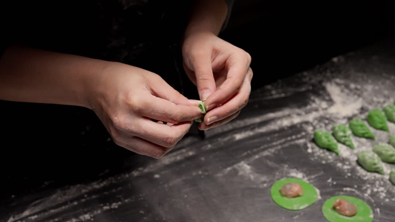 Close-up of Hands Folding Green Dumplings with Meat Filling