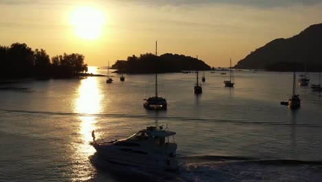 Breathtaking-aerial-landscape-view-capturing-sunset-cruise-on-a-luxury-private-yacht-with-golden-glowing-sun-setting-on-the-horizon-at-Langkawi-island,-Kedah,-Malaysia