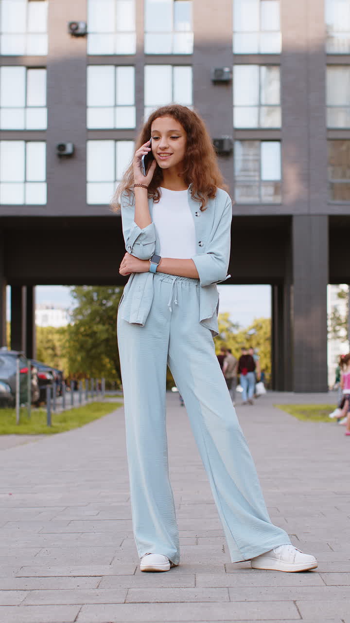 Happy child girl having remote conversation talking on smartphone good news gossip in city street