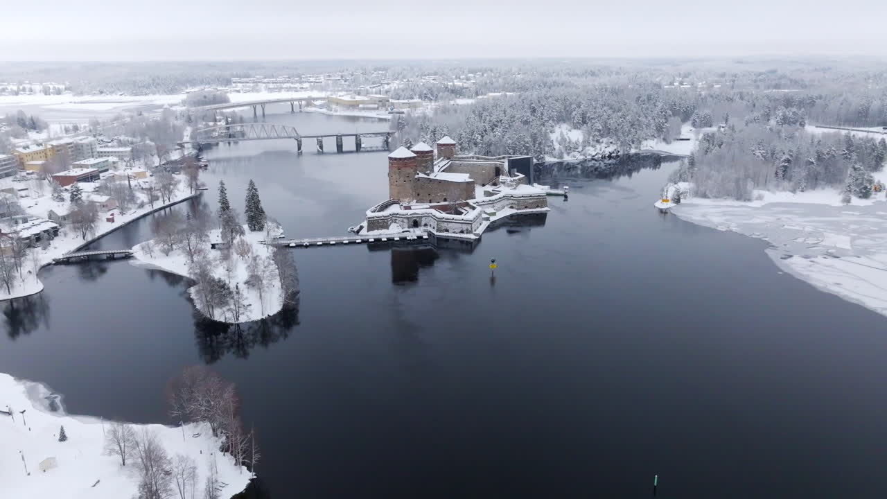 Aerial view tilting toward the snowy Olavinlinna castle, winter day in Finland