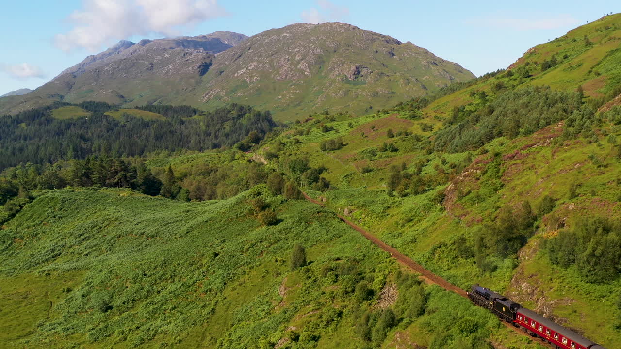 toma de un tren en el viaducto de glenfinnan que desciende lentamente con un dron
