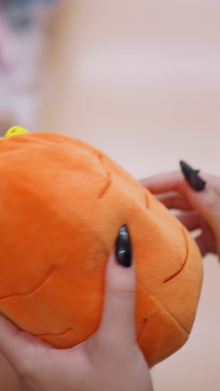 primer plano de una mujer sosteniendo e inspeccionando un vibrante bolso de peluche naranja con detalles verdes en un centro comercial bien iluminado, examina cuidadosamente el material suave mientras hace compras