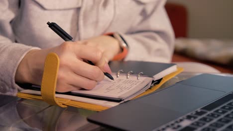 mujer escribe en notas estudiando en casa