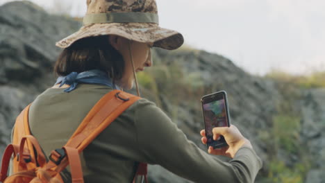 female tourist taking picture of girlfriend in mountains