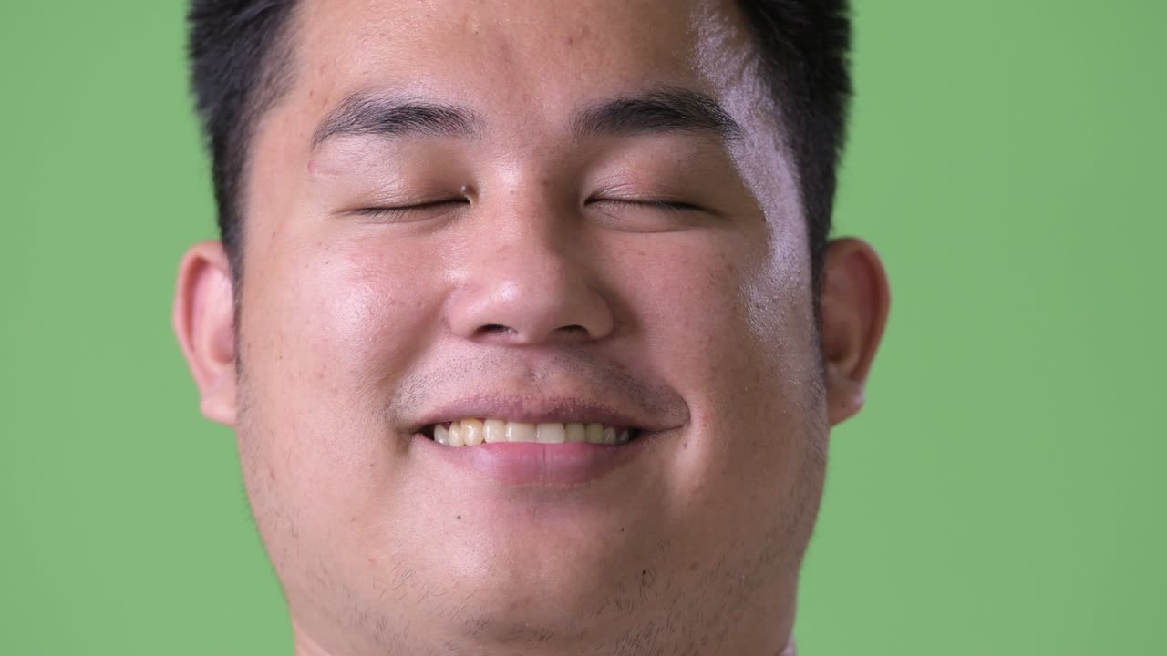 초록색 배경에 젊은 잘생긴 과체중 아시아인