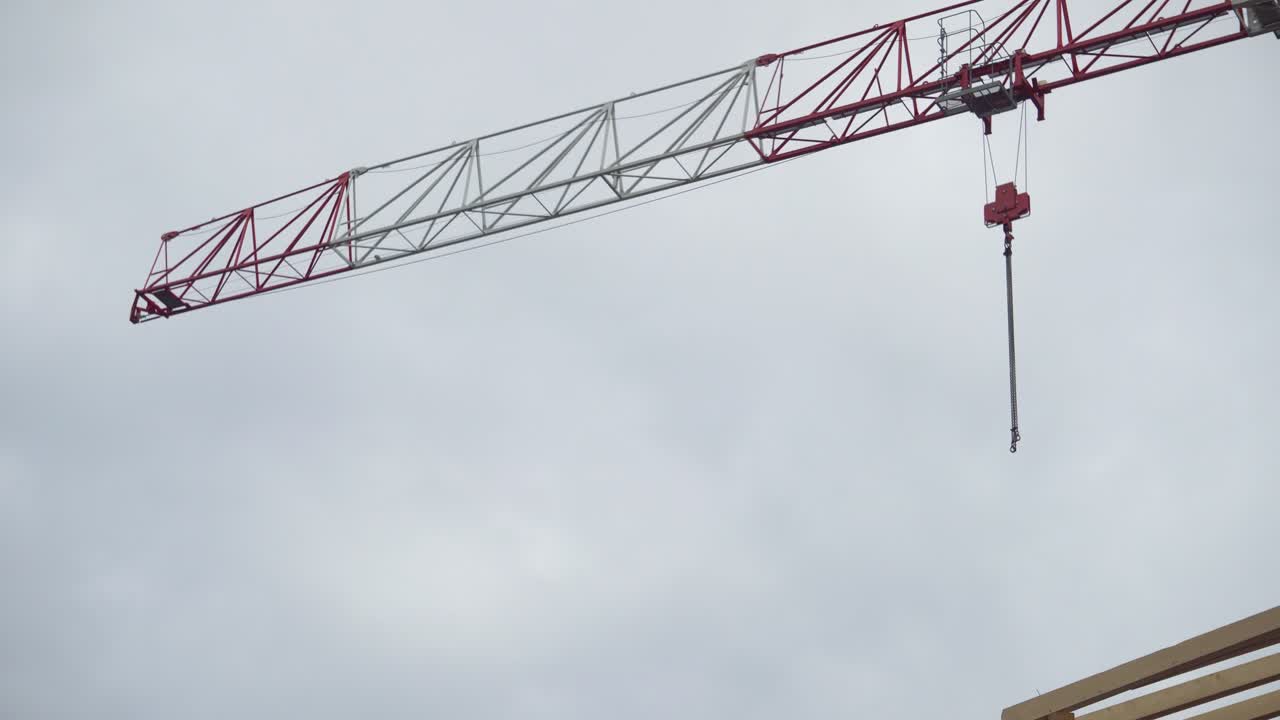 fotografía de una grúa de construcción roja y blanca con cielo nublado en el fondo