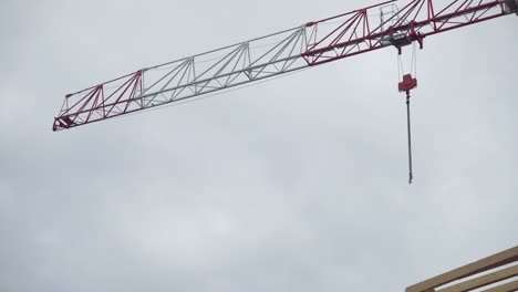 Still-shot-of-a-red-and-white-construction-crane-with-overcast-sky-in-the-background