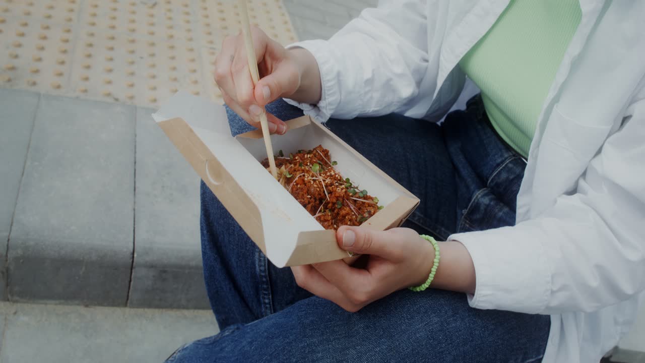 밖에서 아시아 음식을 먹는 여자