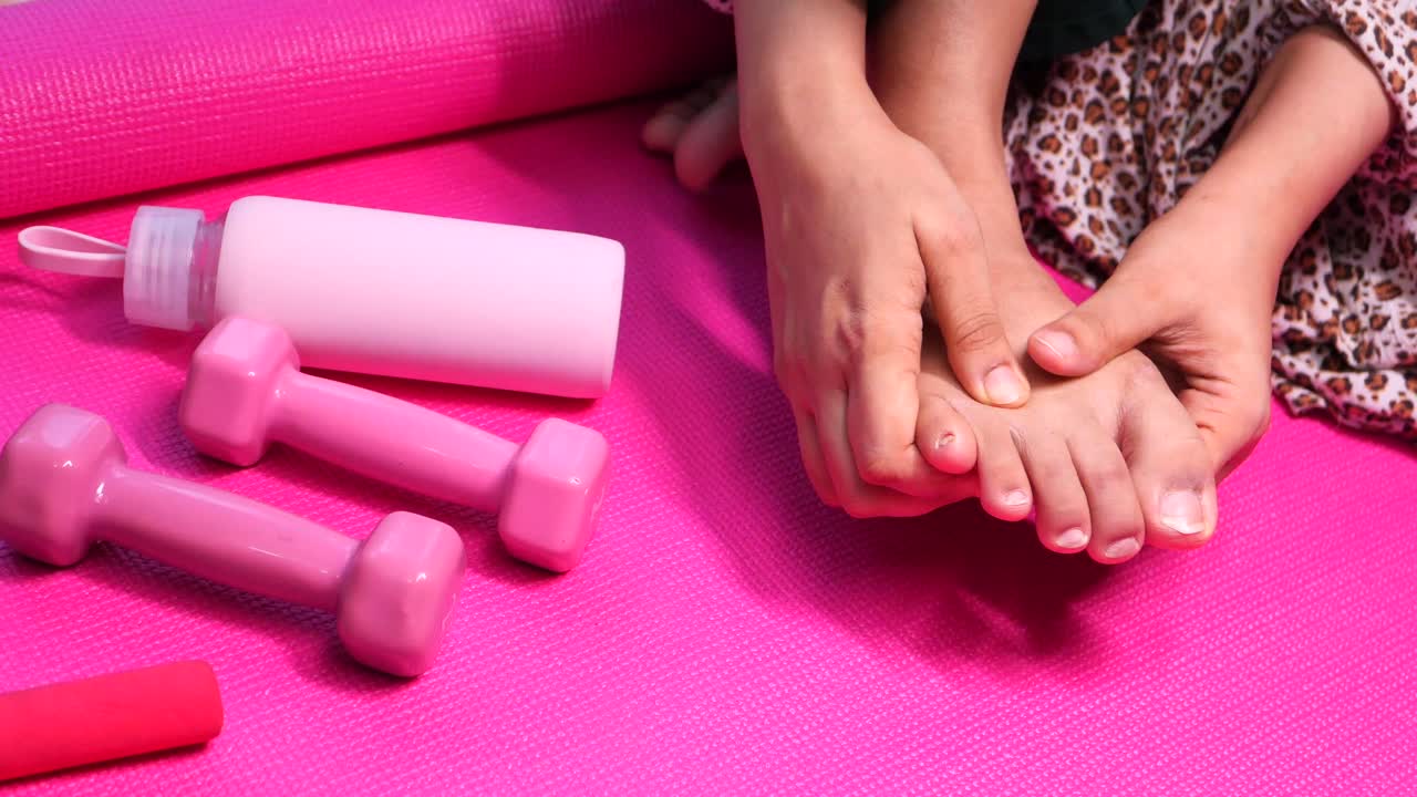Donna seduta su tappetino da yoga con piedi doloranti e attrezzatura fitness