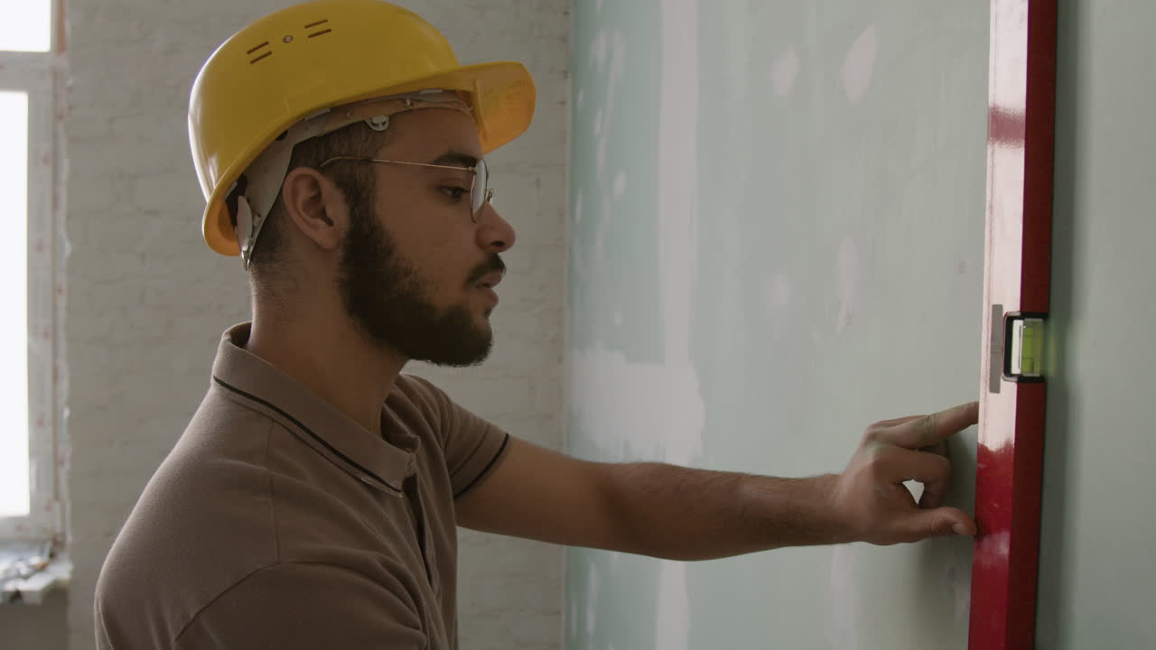 Construction worker using level to measure wall