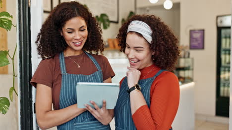 two women using a tablet in a cafe